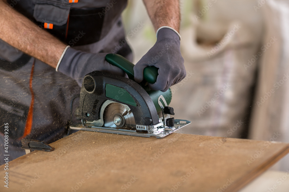 Carpenter cuts plywood with circular saw Carpenter cuts plywood with circular saw