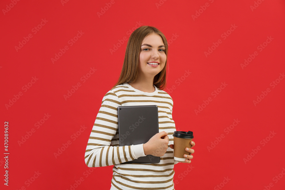 Teenage student with tablet and paper cup of coffee on red background Teenage student with tablet and paper cup of coffee on red background