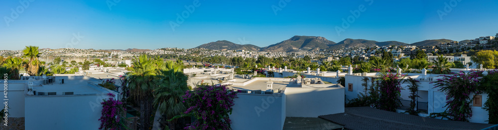 Panorama of the village of Gumbet white houses and crashes and a mountain in the background.