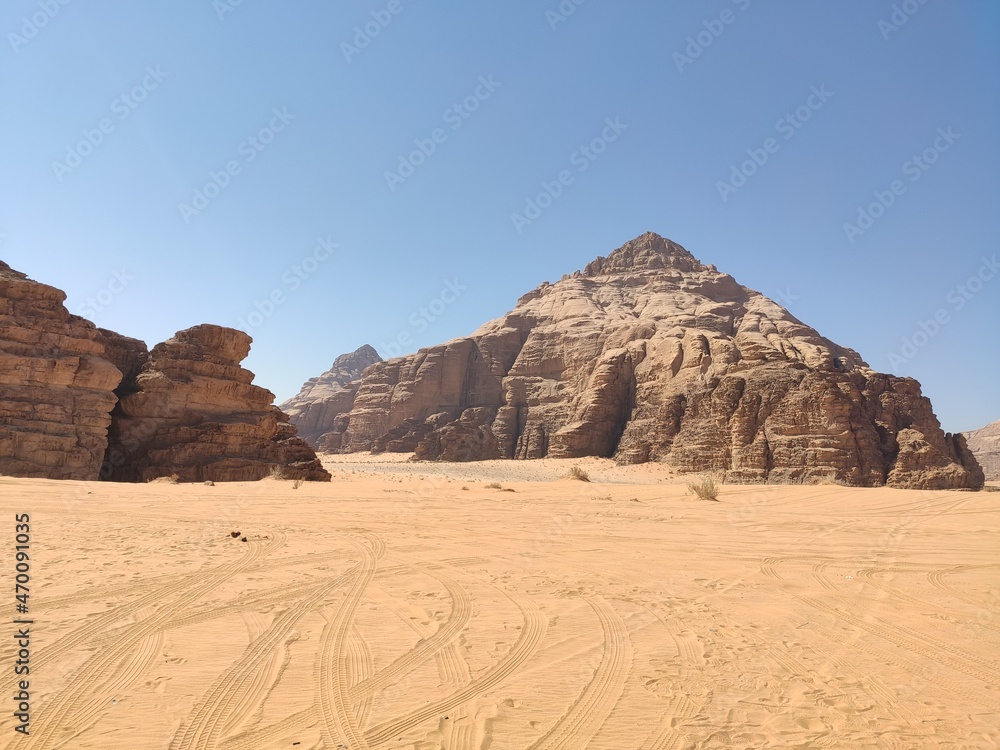 Dans la zone protégée du désert de Wadi Rum en Jordanie, avec de hautes montagnes rocheuses, exploration dans l'inconnu, sous un soleil et forte chaleur, plantation torride, traces de pneu sur route