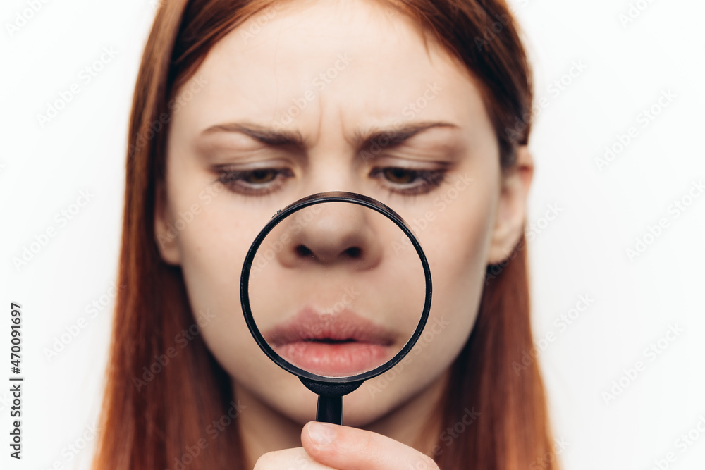 pretty woman grimacing with magnifying glass near face close-up pretty woman grimacing with magnifying glass near face close-up