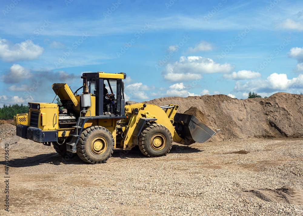 A big yellow tractor is carrying sand in a bucket. Front loader. Work on sand extraction in a quarry. Loading operations. A sand storage area. A big yellow tractor is carrying sand in a bucket. Front loader. Work on sand extraction in a quarry. Loading operations. A sand storage area.