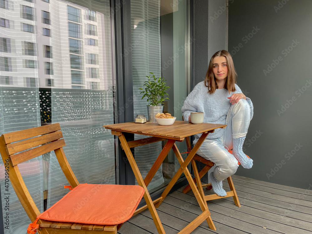 Pretty girl in pajama having breakfast and drinking coffee on balcony or terrace in the morning in city. Pretty girl in pajama having breakfast and drinking coffee on balcony or terrace in the morning in city.