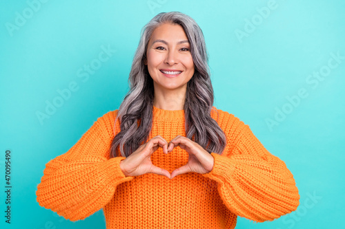 Portrait of attractive cheerful grey-haired woman showing heart sign affection isolated over bright teal turquoise color background photo