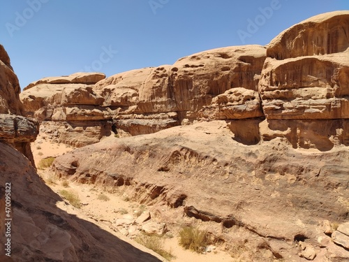  Dans la zone protégée du désert de Wadi Rum en Jordanie, avec de hautes montagnes rocheuses, exploration dans l'inconnu, sous un soleil et forte chaleur, escalade, abri dans l'ombre, pour se reposer
