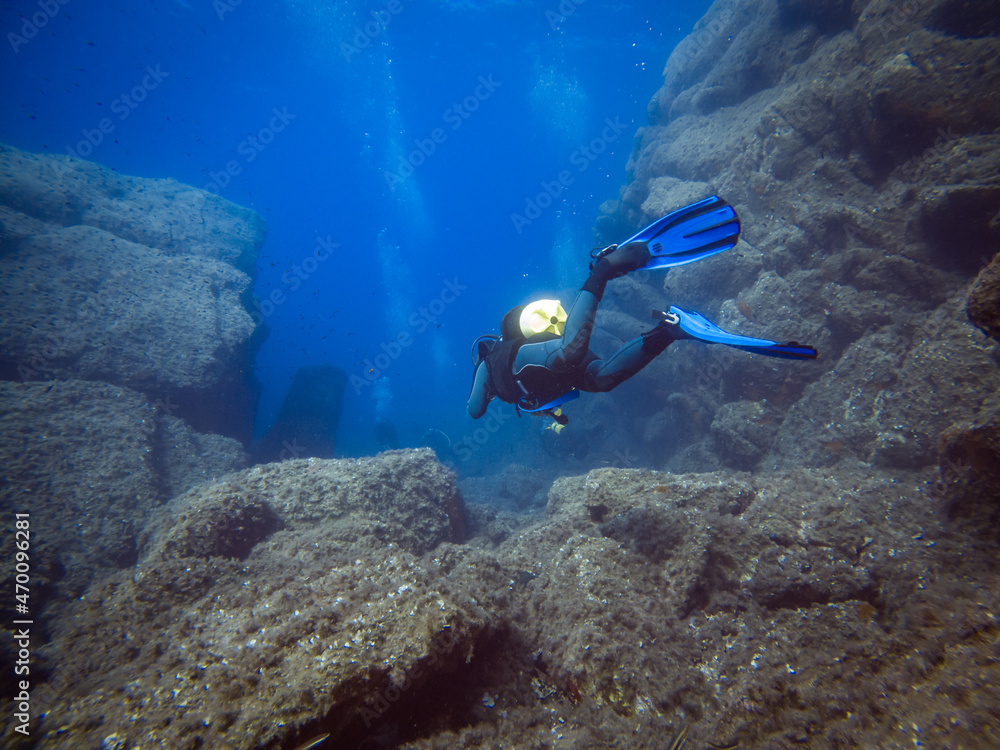 Scuba diver from behind. Diving in clear water. Rocks underwater. Underwater diving. Sardinia diving