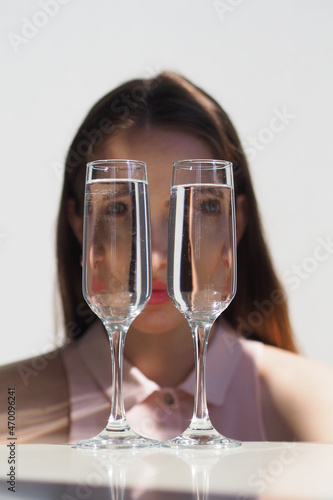 Conceptual surreal portrait Caucasian woman looking through two glasses of water