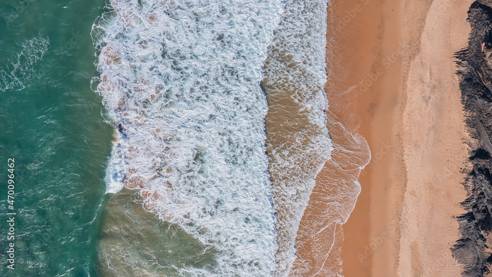 Aerial view of crashing waves on the beach and rocks. Aerial view of sea waves and turquoise water and waves.