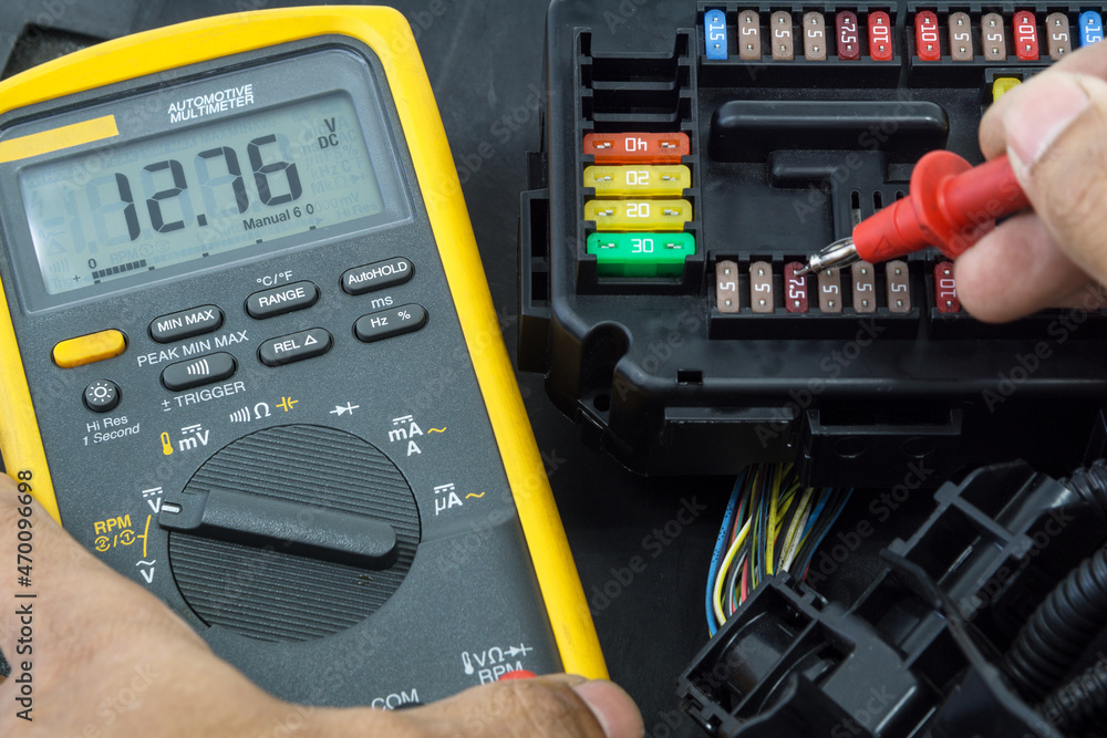 Selective focus an Auto mechanic using a multimeter voltmeter to check Selective focus an Auto mechanic using a multimeter voltmeter to check