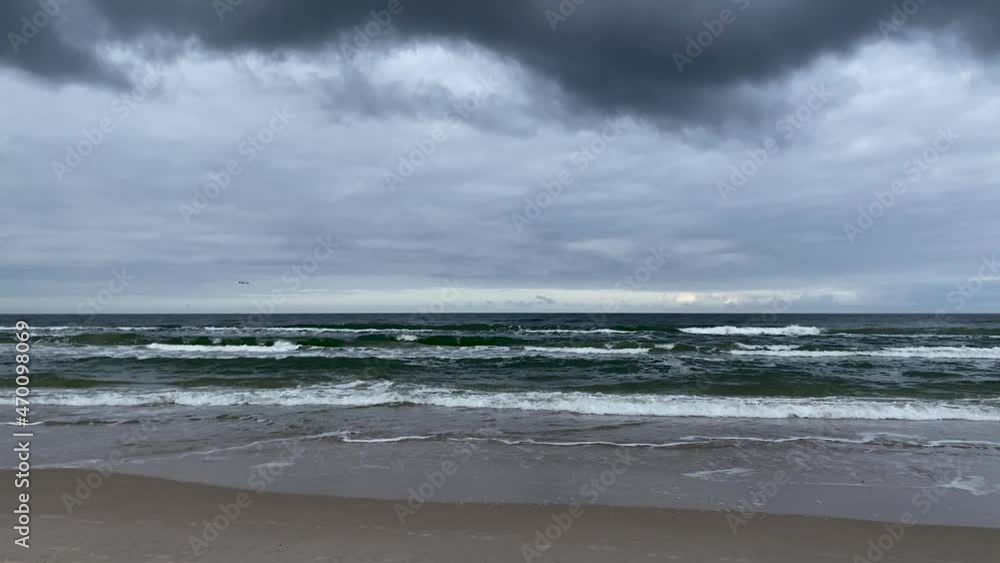 Dark storm clouds over the sea and sandy beach - wide shot