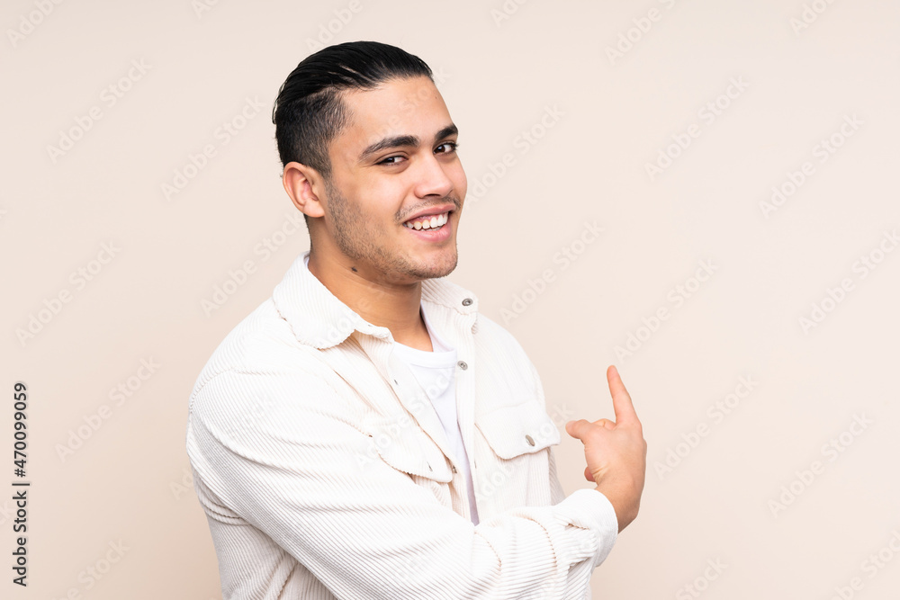 Asian handsome man over isolated background pointing back Asian handsome man over isolated background pointing back