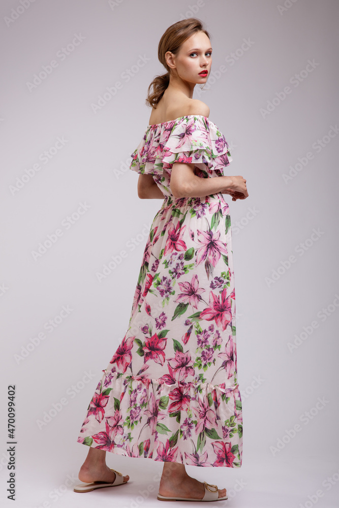High fashion photo of a beautiful elegant young woman in pretty long dress with floral patterns in red color posing over white, soft gray background. Slim figure. Studio Shot. Femininity, tenderness High fashion photo of a beautiful elegant young woman in pretty long dress with floral patterns in red color posing over white, soft gray background. Slim figure. Studio Shot. Femininity, tenderness