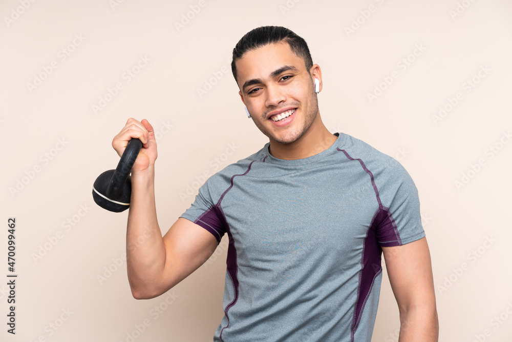 Asian sport man isolated on beige background making weightlifting with kettlebell Asian sport man isolated on beige background making weightlifting with kettlebell