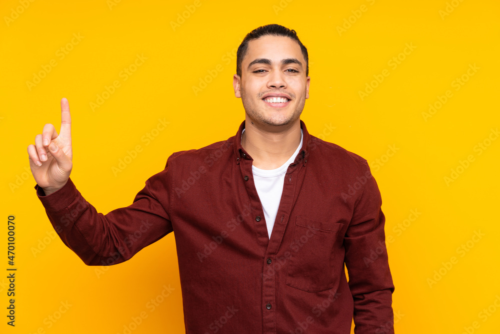 Asian handsome man isolated on yellow background intending to realizes the solution while lifting a finger up Asian handsome man isolated on yellow background intending to realizes the solution while lifting a finger up