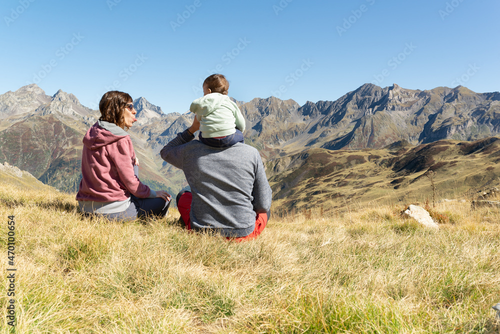 Fototapeta premium Playful couple and baby having a rest during a trekking day at the mountains. Happy family having fun at the mountains. 