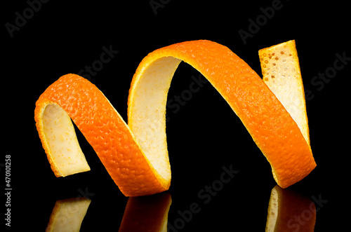 Spiral orange peel on a black background. Citrus twist.
