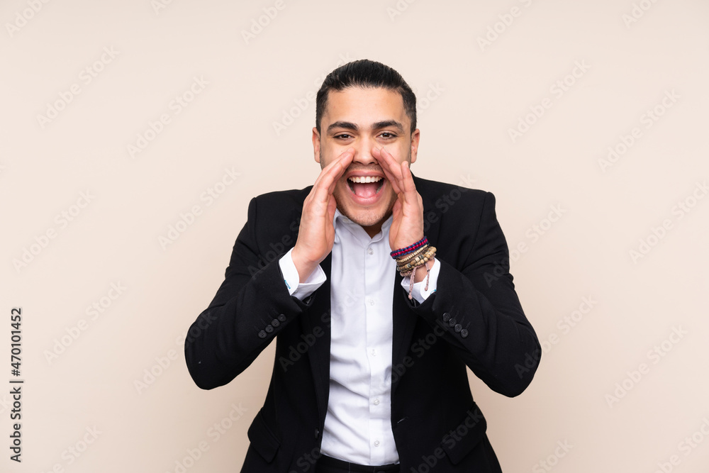 Asian business man isolated on beige background shouting with mouth wide open Asian business man isolated on beige background shouting with mouth wide open