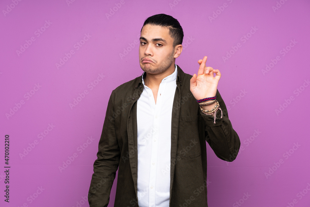 Asian handsome man isolated on blue background with fingers crossing and wishing the best Asian handsome man isolated on blue background with fingers crossing and wishing the best