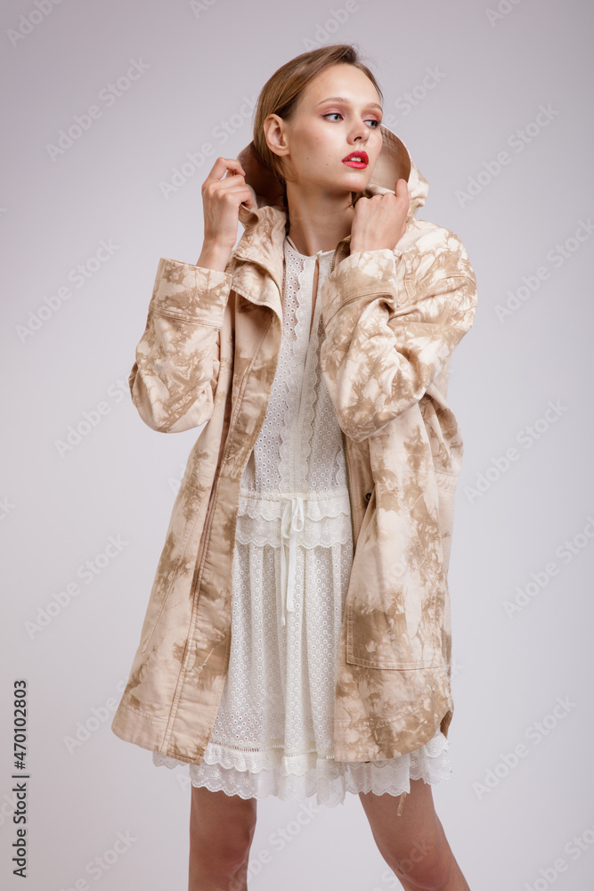 High fashion photo of a beautiful elegant young woman in a pretty jacket with beige streaks, white dress posing over soft gray background. Slim figure. Studio shot High fashion photo of a beautiful elegant young woman in a pretty jacket with beige streaks, white dress posing over soft gray background. Slim figure. Studio shot