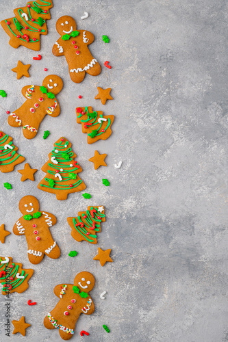 Christmas or New Year food background. Gingerbread cookies decorated with sugar glaze on a gray concrete background. Copy space, top view.