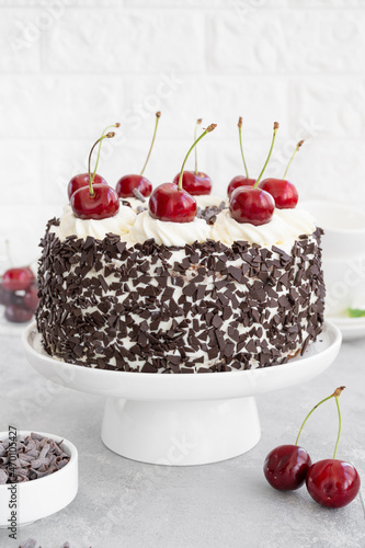 Black forest cake, Schwarzwald pie. Cake with dark chocolate, whipped cream and cherry on a gray concrete background. Copy space.