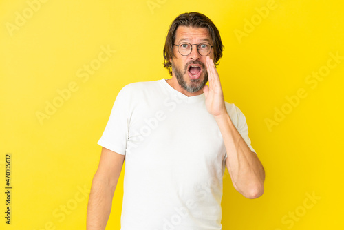 Senior dutch man isolated on yellow background with surprise and shocked facial expression