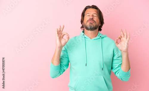 Senior dutch man isolated on pink background in zen pose