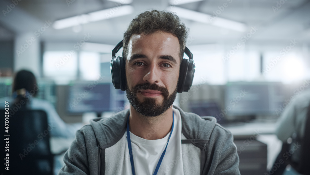 Office: Portrait of Happy IT Programmer Wearing Headphones Working on Desktop Computer. Male Software Engineer Developing App, Video Game. Listening to Podcast, Music Office: Portrait of Happy IT Programmer Wearing Headphones Working on Desktop Computer. Male Software Engineer Developing App, Video Game. Listening to Podcast, Music