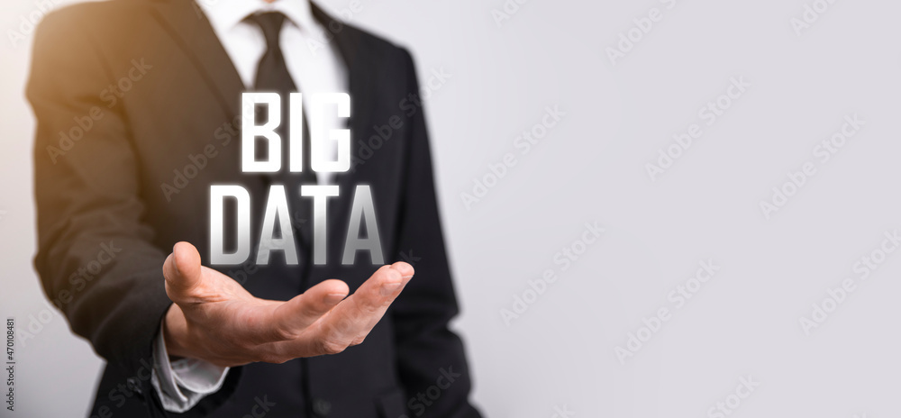 Businessman in a suit on a dark background holds the inscription BIG DATA. Storage Network Online Server Concept.Social network or business analytics representation Businessman in a suit on a dark background holds the inscription BIG DATA. Storage Network Online Server Concept.Social network or business analytics representation