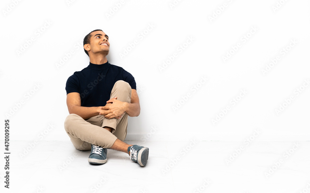 African American man sitting on the floor looking up while smiling African American man sitting on the floor looking up while smiling
