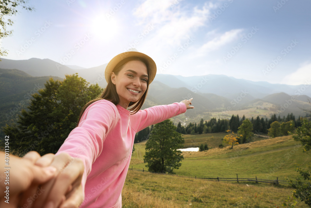Young woman holding boyfriend's hand in mountains, space for text