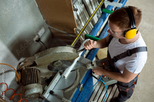 Worker in the workshop cuts pvc profile