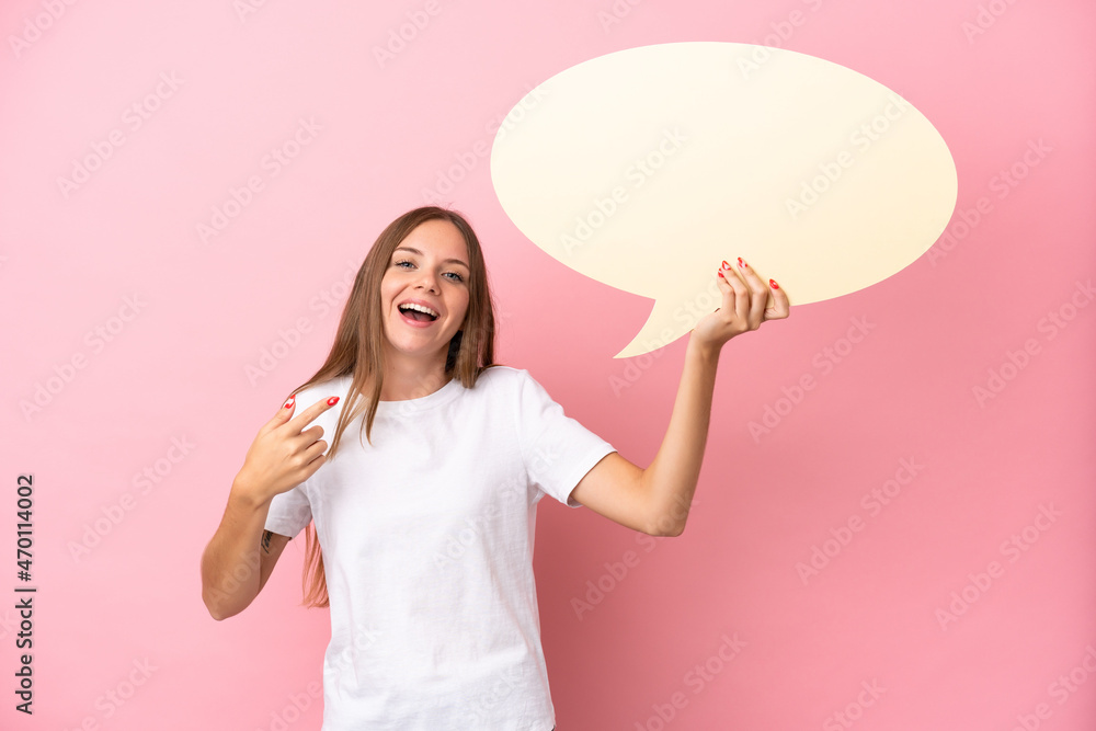 Young Lithuanian woman isolated on pink background holding an empty speech bubble and pointing it Young Lithuanian woman isolated on pink background holding an empty speech bubble and pointing it