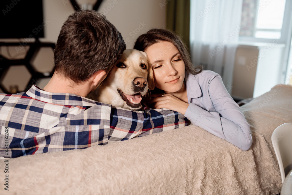 Young couple and their fluffy baby labrador retriever at home in the kitchen Young couple and their fluffy baby labrador retriever at home in the kitchen
