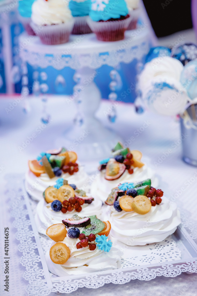 cupcakes with white cream, garnished with berries and fruits, on a white tray with lace edges cupcakes with white cream, garnished with berries and fruits, on a white tray with lace edges