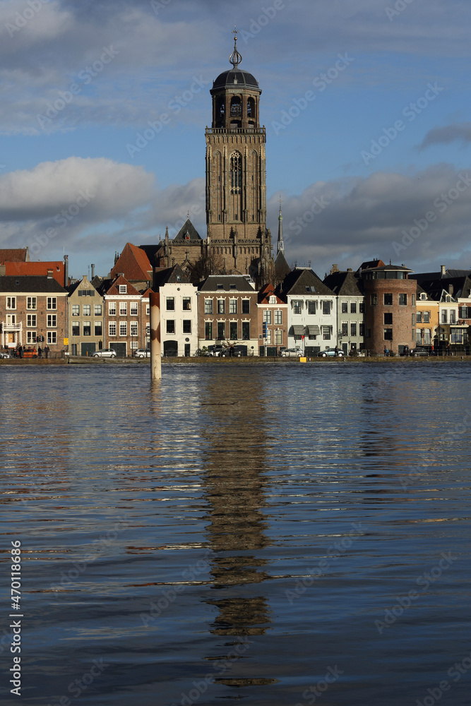 The facades of beautiful old buildings and the tower of the Great Church in the city of Deventer, The Netherlands, with reflection in the river IJssel
