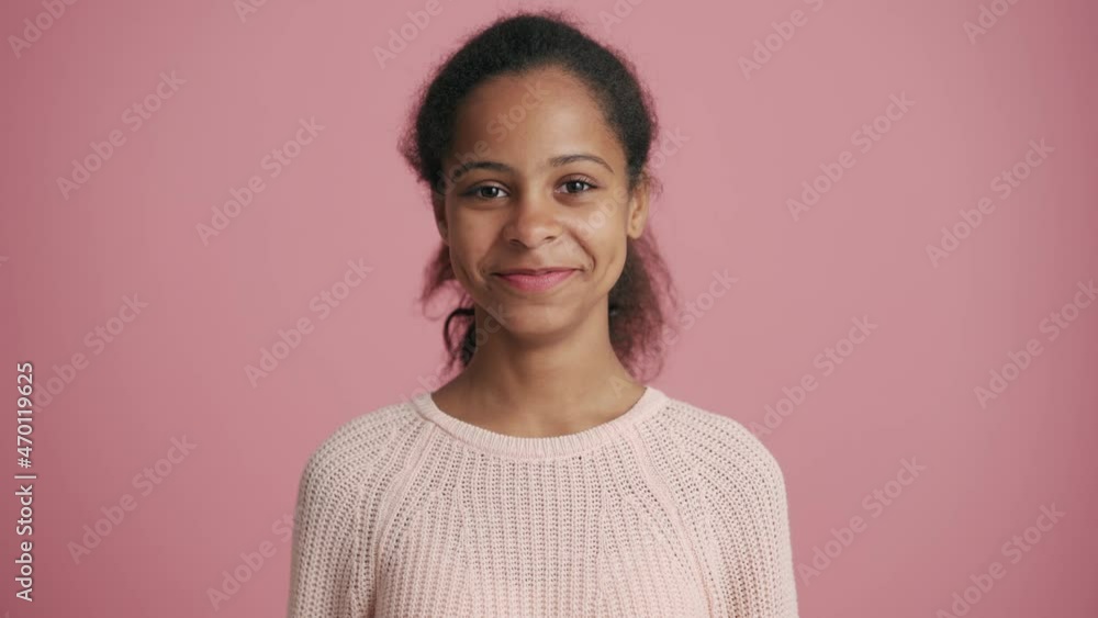 Smiling African little girl looking at the camera in the pink studio Smiling African little girl looking at the camera in the pink studio