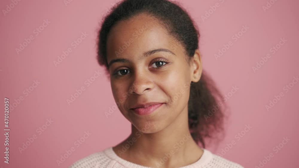 Handsome African little girl looking at the camera in the pink studio