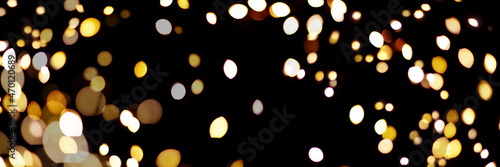 Banner made with gold light blurred. Abstract boken texture. Festive background. Glitter light spots on black background.