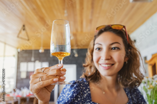 Bild auf Leinwand Happy asian woman tastes a new brand of cognac or grappa from a glass at the winery