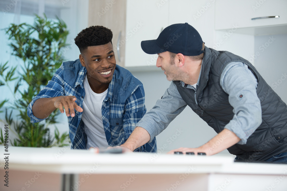 Fototapeta premium carpenter and apprentice installing luxury fitted kitchen
