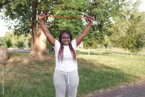 a dark-skinned girl trains in the park outdoors performing exercises with a rope
