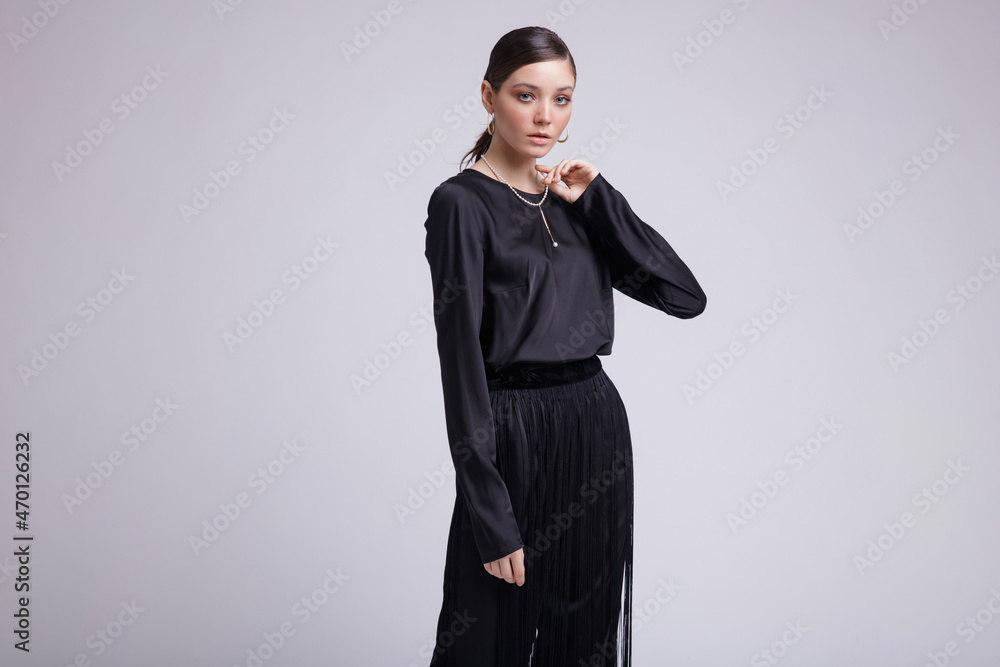 High fashion photo of a beautiful elegant young woman in a pretty black blouse, fringe trousers, accessories over white background. Studio Shot. Gathered dark hair. Slim figure High fashion photo of a beautiful elegant young woman in a pretty black blouse, fringe trousers, accessories over white background. Studio Shot. Gathered dark hair. Slim figure
