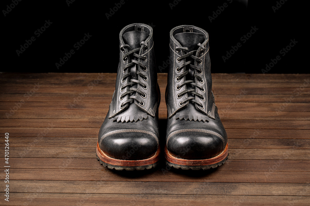 Hand crafted black leather high boots on wooden background