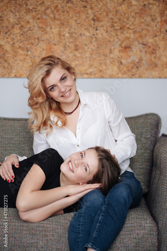 Beautiful mother and her pretty daughter teenager smiling and posing at home.