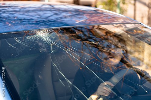 Shocked woman in car with broken windshield  and cracks. Car accident. Selective focus