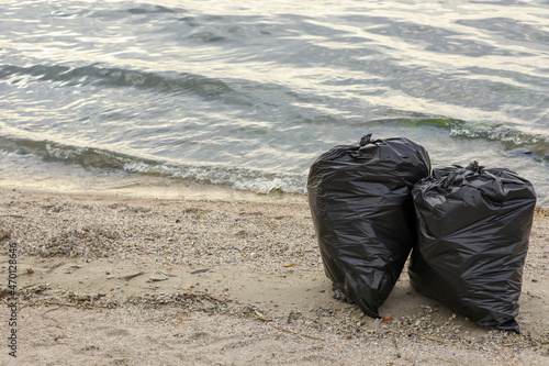 Trash bags full of garbage on beach. Space for text © New Africa