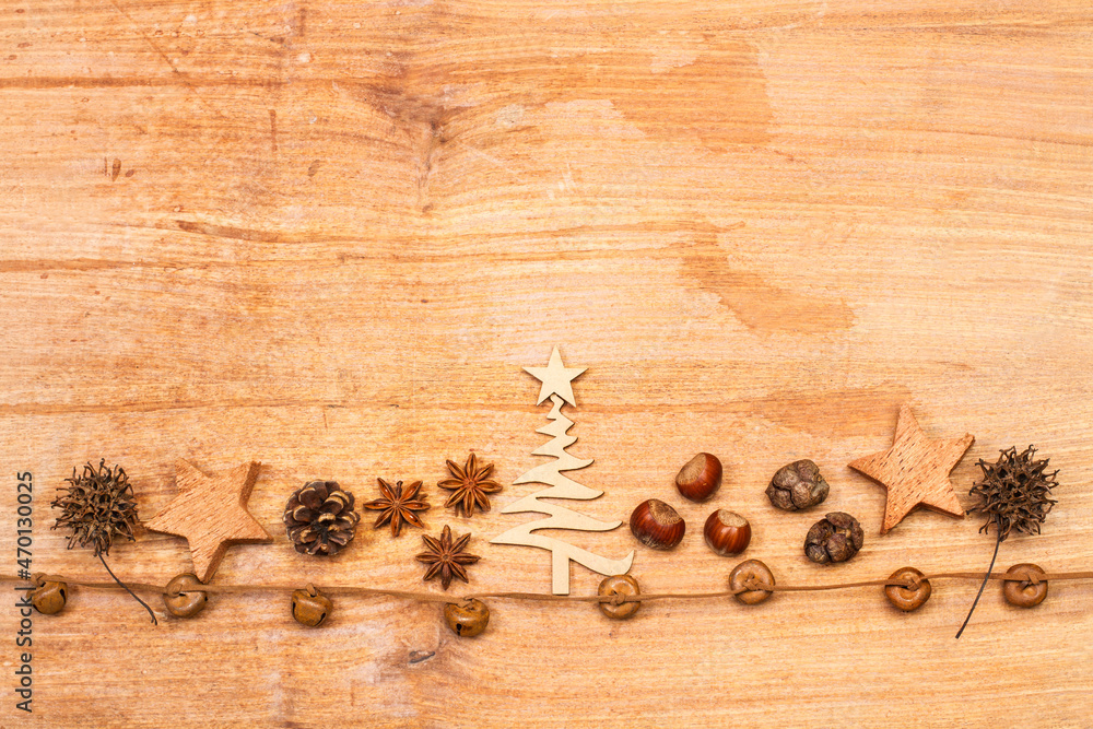 Naklejka premium Composición de Navidad con piñas secas, árbol, estrellas, castañas, anis estrellado y cascabeles sobre un fondo de madera rústico. Vista superior. Copy space