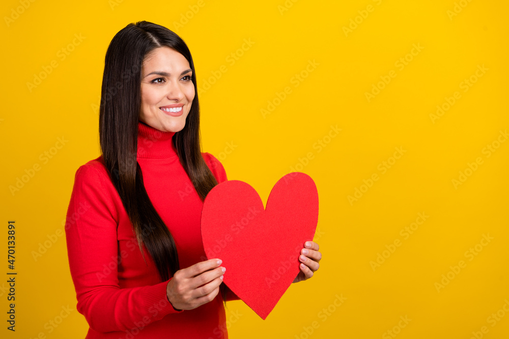Profile portrait of charming cheerful lady hold heart card look empty space isolated on yellow color background Profile portrait of charming cheerful lady hold heart card look empty space isolated on yellow color background