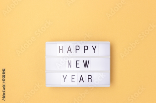 Happy New Year. White lightbox with phrase on a golden background with copy space.